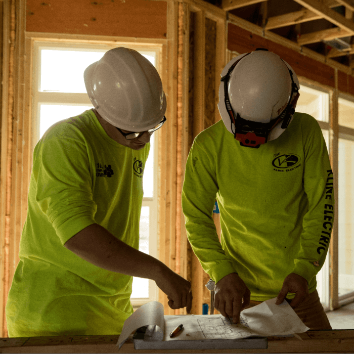 two Kline Electric employees reviewing a blueprint plan